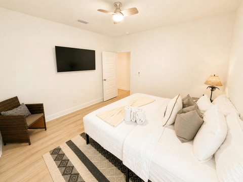 A comfortable bedroom with a mounted smart TV and plush bedding—settle in for a relaxing stay just minutes from the sand.