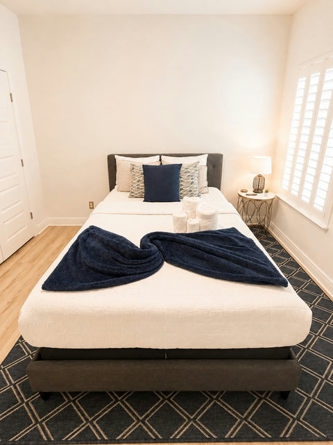 Crisp white bedding with navy accents makes this bedroom feel fresh and inviting—a peaceful spot to end your day.