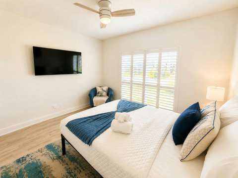 Kick back in this stylish bedroom featuring a mounted smart TV, a comfy accent chair, and beachy blue accents throughout.