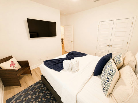 Stream your favorites on the mounted TV in this comfortable bedroom—warm wood floors and layered bedding complete the space.