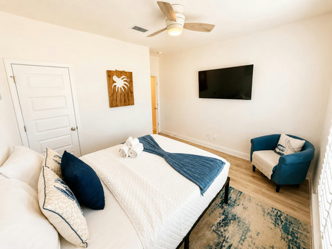 Relax and stream your favorites on the mounted TV in this comfortable, sunlit bedroom with classic coastal styling.