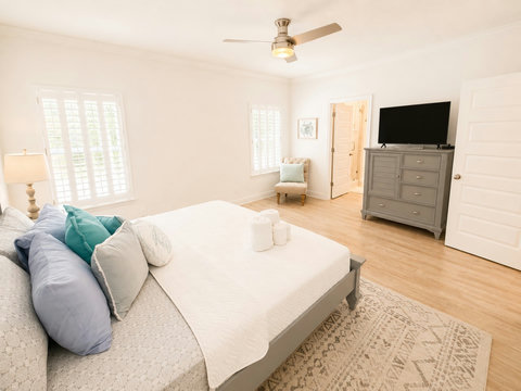 A generous bedroom with a cozy sitting chair, dresser, and mounted TV—your private space to relax and recharge.
