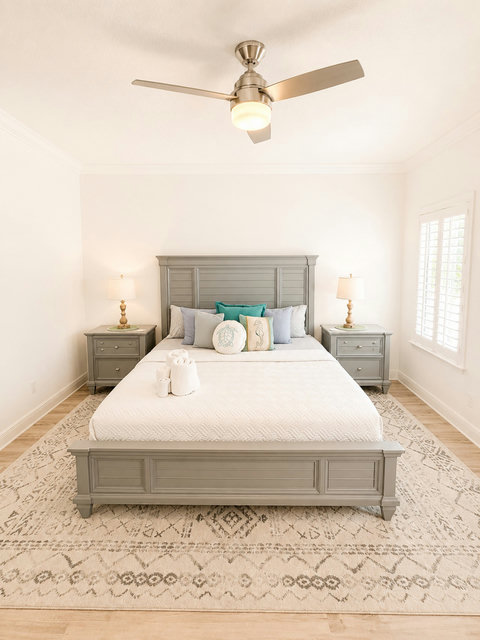 Rest easy in this serene bedroom retreat, with a plush bed, coastal accents, and soft natural light through plantation shutters.