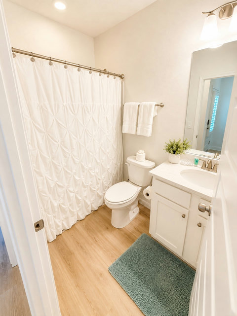 A clean, fresh full bathroom with a shower-tub combo and plush towels, keeping busy beach mornings running smoothly.