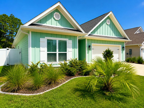 Curb appeal that says vacation—this charming seafoam-green cottage with crisp white trim and lush tropical landscaping is your home base on 30A.