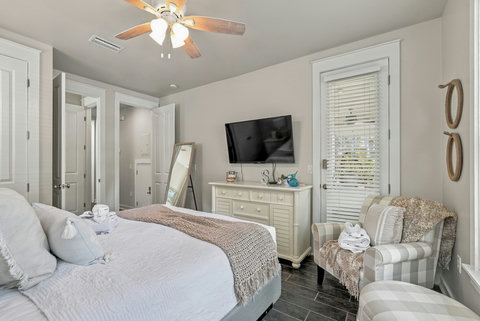 Guest bedroom with TV, dresser and armchair