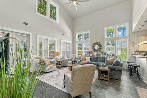 Bright living room with tall windows and ceiling fan