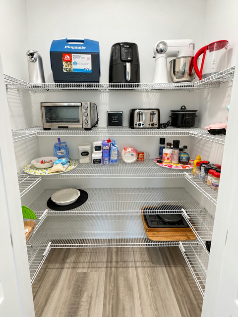 Walk-in pantry stocked with small appliances and cooler