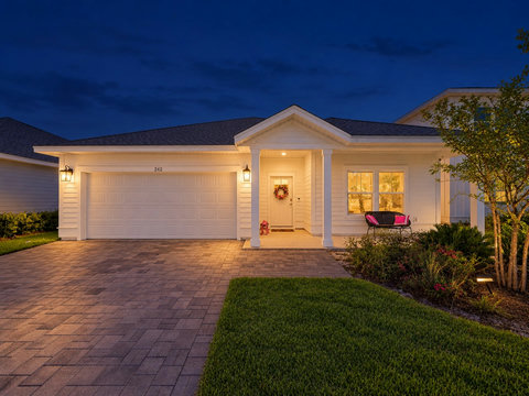 Front exterior at dusk with paver driveway and two-car garage