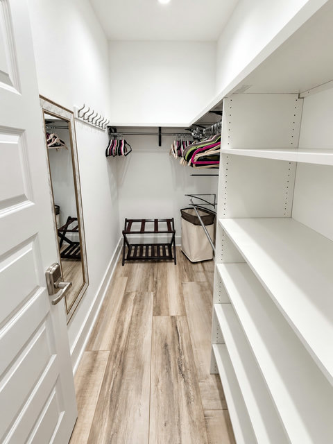 Primary walk-in closet with shelving and luggage rack