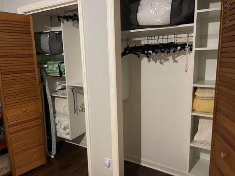 Master Bedroom closet with hangers, iron and ironing board; extra pillows, blankets and comforters