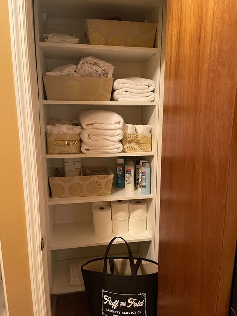 Main bathroom linen closet with extra queen sheet sets, towels, toilet paper, body wash, shampoo, conditioner, heating pad and laundry basket 