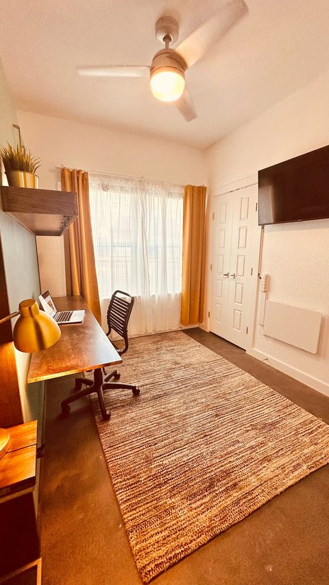 This downstairs bedroom is equipped with a tv, a closet, a small fold-down desk under the tv, a full bathroom, and a Murphy bed which, when closed, provides a large lighted workspace with a charging station for remote work needs. 