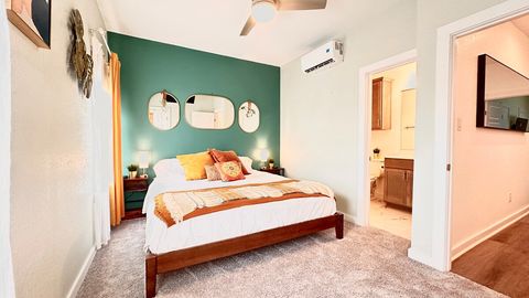 This bedroom now features a ceiling mounted television, walk-in closet with luggage rack, an attached full bathroom, blackout blinds, and dimmable lamps with charger ports on both nightstands. (please bring your own cords)