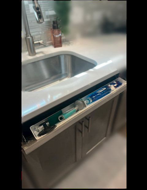 The panel in front of the sink tilts out to hold all the dish-washing essentials like dish soap, dishwasher pods, and a scrub brush.  This feature helps keep surfaces clear and clutter free.  