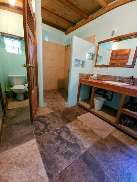 Spacious bathroom with private toilet room, walk-in shower & custom-built cement vanity.