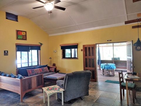 Living room with 2 twin day-beds & recliner, large live-edge custom made coffee table, desk & chair.  Note dining table with stools on fully screened deck.