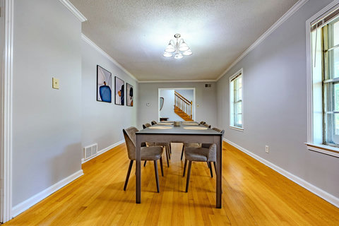 Host meals or meetings in the spacious dining room featuring a large table that seats up to 10. Modern artwork adds style, while wooden floors create a warm, elegant vibe perfect for family dinners or casual gatherings.