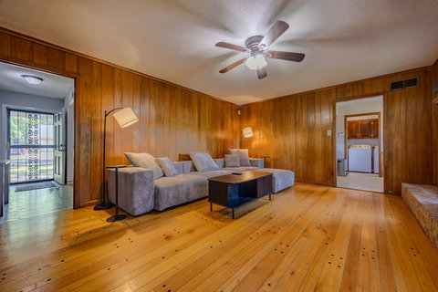 Enjoy the spacious living room with a massive sectional, cozy functional fireplace, 65" smart TV with sound bar/subwoofer, ceiling fan, coffee table, and sleek wooden floors. Perfect for relaxing, streaming, or spending time with family and friends.