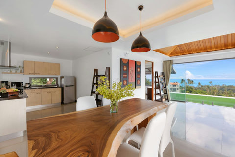 Modern fully-equipped kitchen and dining area with wooden table for 8, opening directly onto the pool and terrace
