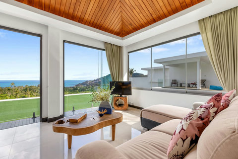 Expansive living room with wrap-around sea views, vaulted teak ceiling and comfortable seating perfect for families