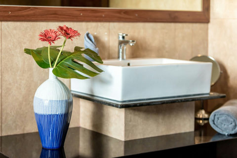 Bathroom vanity detail with designer vessel sink, fresh flowers and premium toiletries