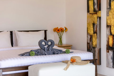 Premium bedding with artistic towel arrangement and traditional Thai touches - daily maid service included