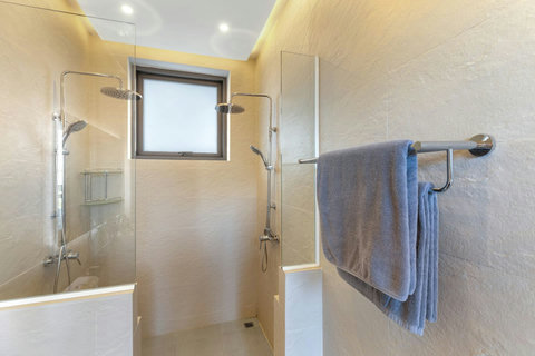 Clean modern shower with rainfall head, window light and fresh towels provided daily