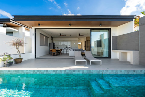Inviting pool deck with covered terrace, lounge furniture and seamless indoor-outdoor living - relaxation perfected