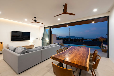 Sophisticated living and dining area with wooden table, modern furnishings and stunning twilight views - perfect entertaining space