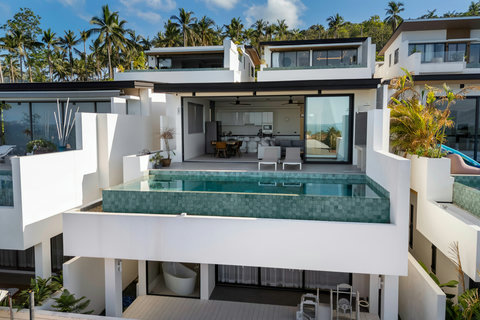 Stunning modern villa exterior with multi-level architecture, infinity pool and lush tropical palms - paradise found