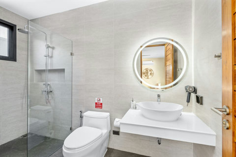 Clean modern bathroom with walk-in shower, vessel sink, golden circular mirror and contemporary fixtures throughout