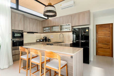 Fully equipped modern kitchen with island seating, premium appliances and wooden dining table for 6