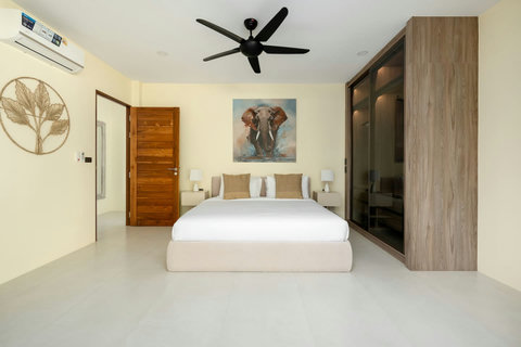 Additional bedroom with comfortable bed, ceiling fan, modern elephant artwork and elegant wood wardrobe storage