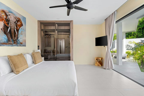 Third bedroom with artistic elephant decor, air conditioning, crisp linens and terrace doors to tropical gardens