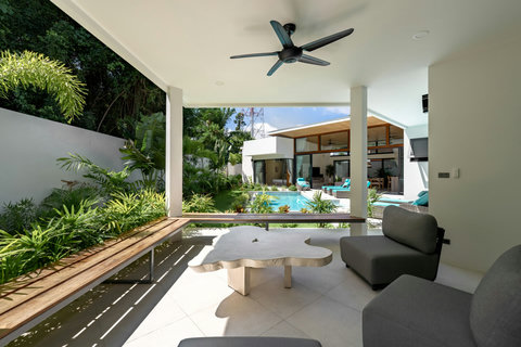 Shaded outdoor terrace with wooden deck, comfortable seating and direct pool access - perfect for alfresco dining
