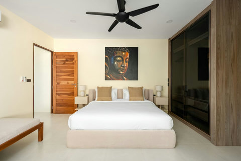 Clean comfortable bedroom with wood accents, ceiling fan and modern Thai artwork - peaceful accommodation