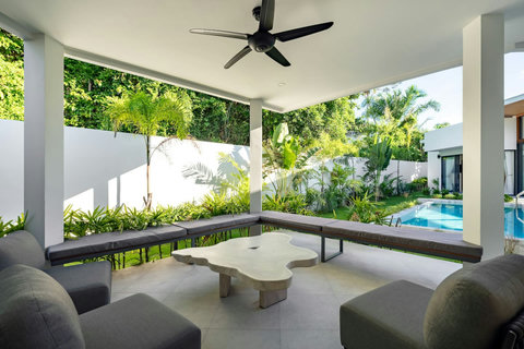 Covered outdoor sala with comfortable lounge seating, ceiling fans and serene pool-garden views for relaxing