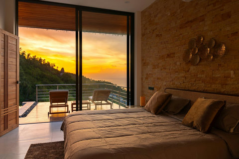 Master bedroom with stunning sunset terrace views and textured wood wall - romantic hillside escape