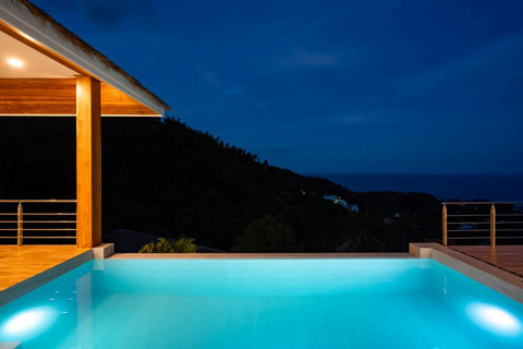 Evening pool illuminated at dusk with mountain silhouettes and tropical atmosphere - luxury villa Koh Samui