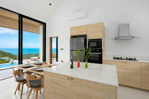 Modern open kitchen with ocean views, island seating and premium appliances - gourmet cooking paradise