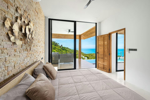 Elegant bedroom with stone wall feature and open terrace doors to pool - luxury Koh Samui villa