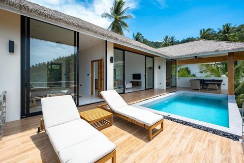 Daytime pool terrace with wooden deck, sun lounger and mountain backdrop - perfect outdoor living