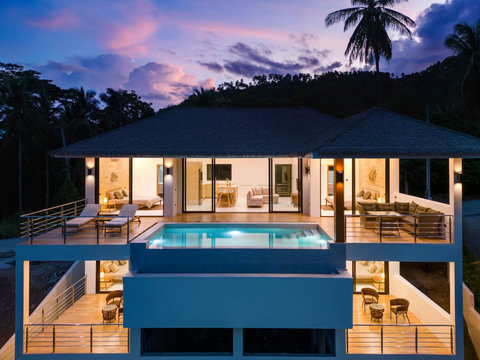 Evening villa illuminated at dusk with infinity pool and tropical hillside setting - luxury Koh Samui
