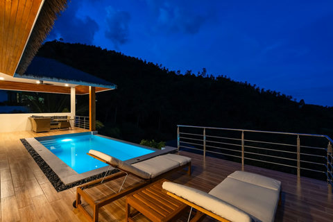 Twilight pool deck with sala and jungle view - infinity pool illuminated at dusk luxury villa