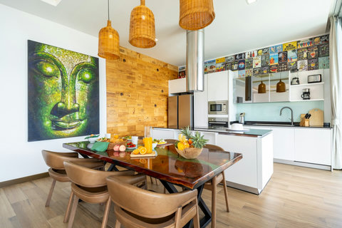 Dining area with feature mural and open-plan kitchen at Villa Yoco, Koh Samui