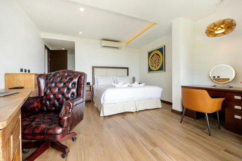 Bedroom with leather armchair, work desk and warm wood flooring at Villa Yoco, Koh Samui
