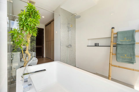 Luxurious bathroom with soaking tub, walk-in shower and tropical plant at Villa Yoco