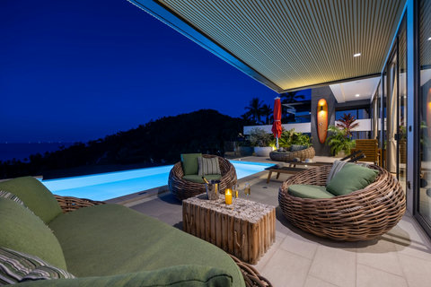 Illuminated poolside terrace lounge at dusk with sea views at Villa Yoco, Koh Samui