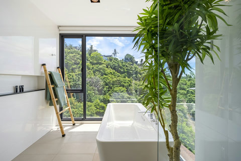 Freestanding bathtub beside floor-to-ceiling window with tropical views at Villa Yoco